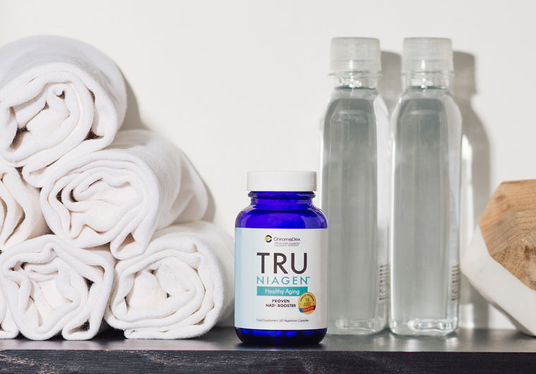 Image of NAD supplement bottle from Tru Niagen on counter with a glass of water